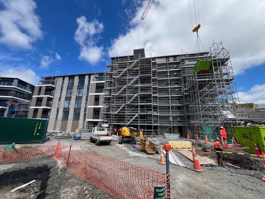 Multi-storey apartment building under construction with scaffolding and earthworks around the basement