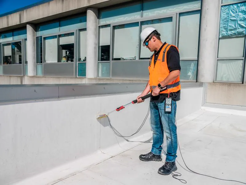 Operator testing a vertical membrane upstand with a Detec low-voltage roller